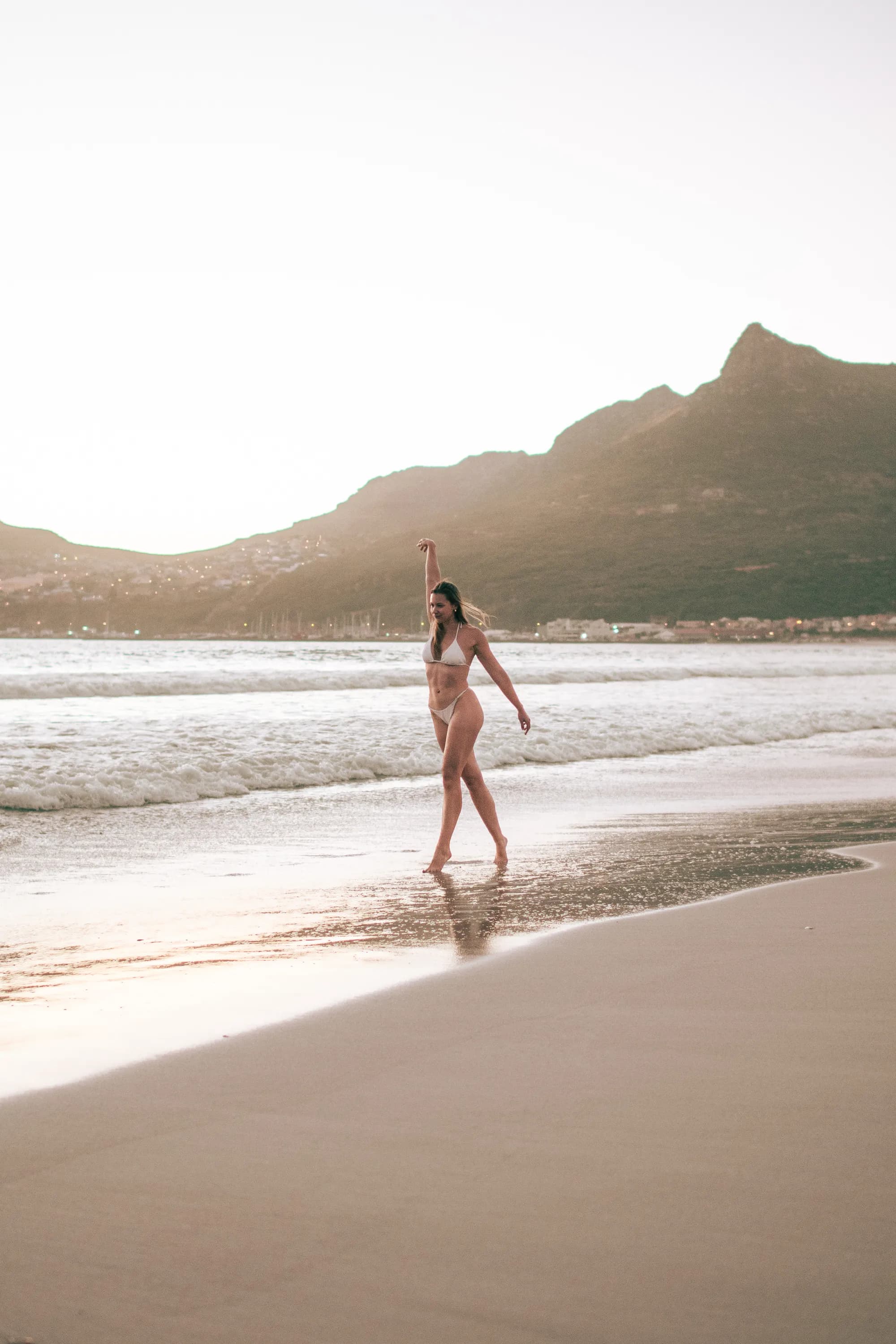 Madison walking on beach, arm raised in freedom